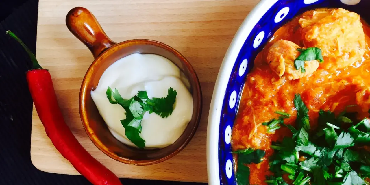 Aksamitny kurczak po indyjsku w pomarańczowym sosie, podany z jogurtem i ostrą papryczką chili.