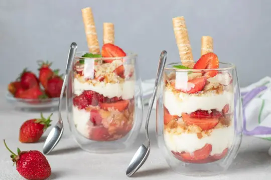 Szybki deser z mascarpone i biszkoptami, przełożony truskawkami, udekorowany wafelkami i miętą. Idealny na letnie popołudnie.