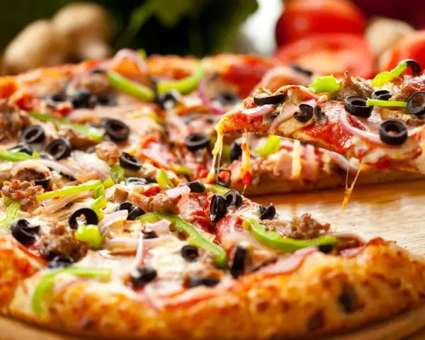 Gotowe ciasto na pizzę z mnóstwem dodatków: pepperoni, oliwki, papryka, cebula i ser. Idealne na wieczór filmowy!