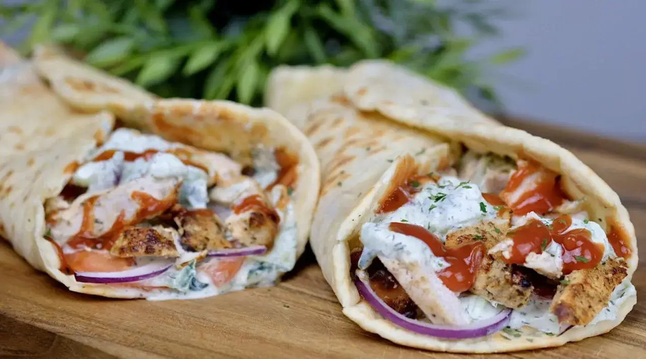 Dwa pyszne wrapy z kurczakiem gyros, polane sosem i ketchupem, na desce.